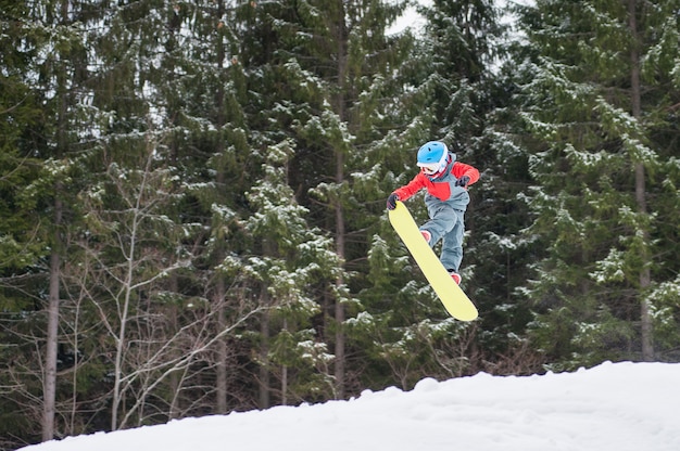 Der Junge springend auf das Snowboard