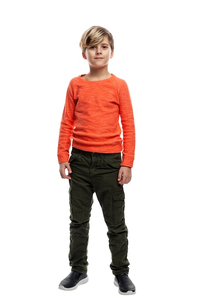 Der Junge steht. Ein Typ in dunkler Jeans und einem orangefarbenen Pullover. Isoliert auf weißem Hintergrund. Vertikal.