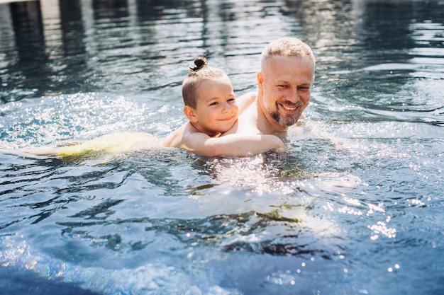 Der junge Vater bringt seinem kleinen Sohn bei, im Schwimmbad zu schwimmen