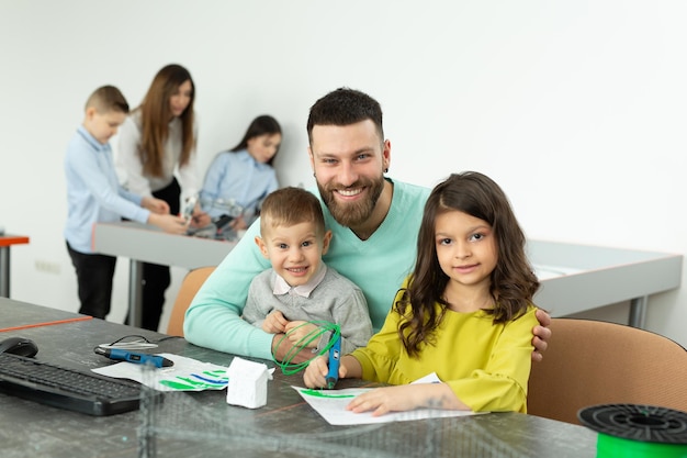 Der junge Vater mit seinem Sohn und seiner Tochter zeichnet im Robotikunterricht eine Zeichnung mit einem 3D-Stift