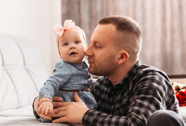 Foto der junge vater sieht seine tochter infant in einem hellen raum zärtlich an