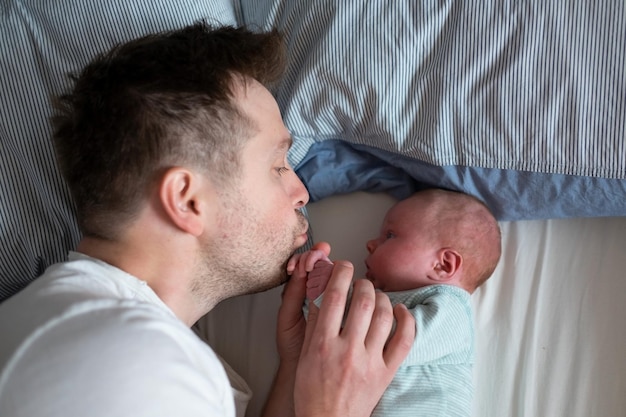 Der junge Vater verbringt Zeit mit seinem neugeborenen Mädchen im Bett Vaterschaftskonzept