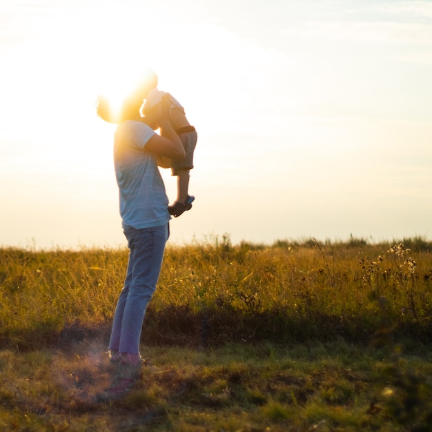 Der junge Vater wirft seinen süßen und kleinen Sohn an die frische Luft. Vatertag, Vater und sein Sohn Baby spielen und umarmen sich im Freien.