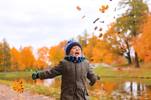 Der Junge wirft Herbstblätter Herbstartikel Ein glückliches Kind Herbst