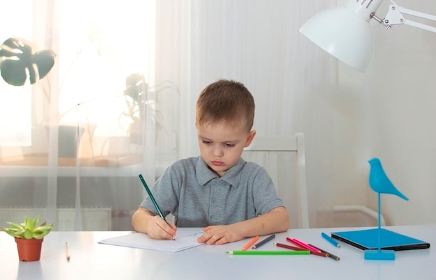 Der Junge zeichnet in seinem Zimmer an seinem Schreibtisch Das Kind beschäftigt sich zu Hause mit Kreativität Das Konzept der Kreativität von Kindern Selektiver Fokus