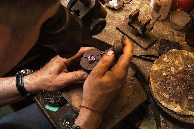 Der Juwelier nimmt einen Stein aus der Fassung eines goldenen Rings, der Schmuck repariert