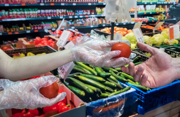 Der Käufer in Handschuhen wählt während einer Pandemie Gemüse