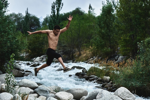 Foto der kasachische muskelsportler trainiert und trainiert am fluss in der natur. asiatischer hübscher macht extremes fitnesstraining im freien