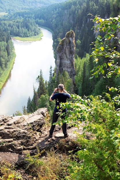 Der kaukasische Mann steht zurück und macht ein Foto von der schönen Landschaft des Teufelsfingers, des Flusses Usva