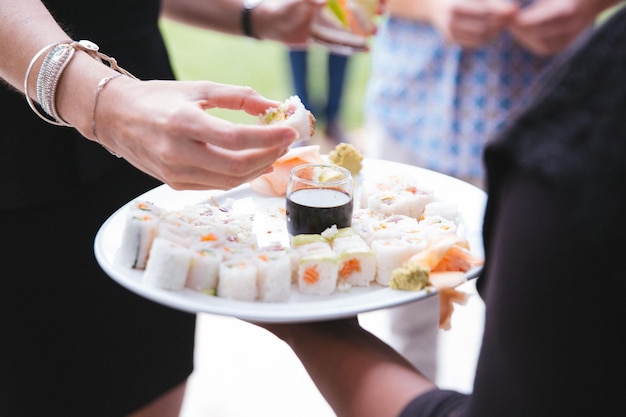 Der Kellner hält Sushi auf dem Teller, während die Frau isst