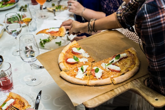 Der Kellner legt Pizza auf die Teller der Gäste, Restaurant-Service