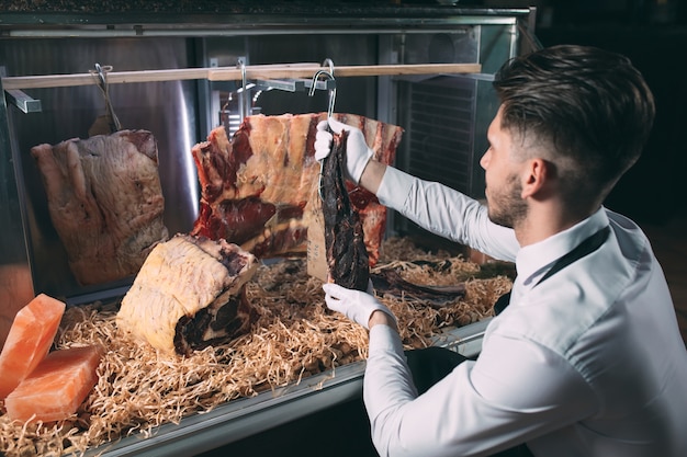 Foto der kellner oder koch bekommt trockenes fleisch in den kühlschrank.