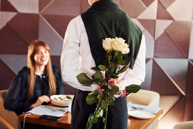 Der Kellner schenkt einer Frau Blumen Im Inneren des neuen modernen Luxusrestaurants