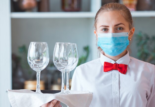 Der Kellner serviert einen Tisch in einem Café in einer Schutzmaske.