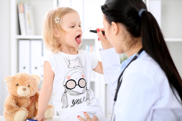 Foto der kinderarzt kümmert sich um das baby im krankenhaus. kleines mädchen wird vom arzt mit stethoskop untersucht. gesundheitsversorgung, versicherung und hilfskonzept.