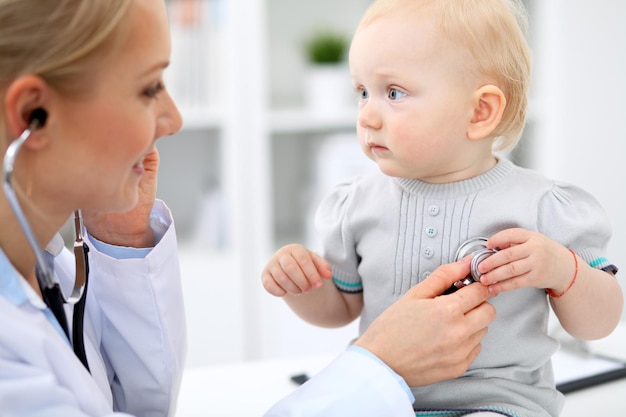 Foto der kinderarzt kümmert sich um das baby im krankenhaus. kleines mädchen wird vom arzt mit stethoskop untersucht. gesundheitsversorgung, versicherung und hilfskonzept.