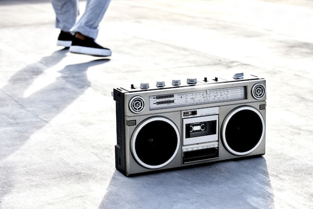 Der Klang von Musik Hochwinkelaufnahme einer Boombox auf dem Boden mit einer nicht erkennbaren Tänzerin im Hintergrund