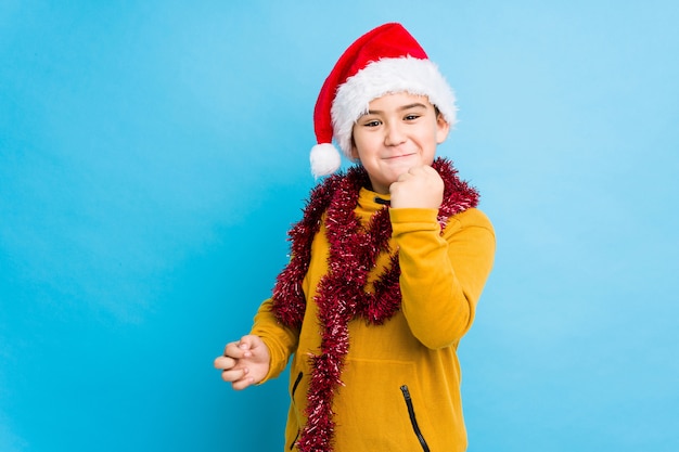 Der kleine Junge, der Weihnachtstag einen Sankt-Hut tragend feiert, lokalisierte das Zeigen der Faust zur Kamera, aggressiver Gesichtsausdruck.