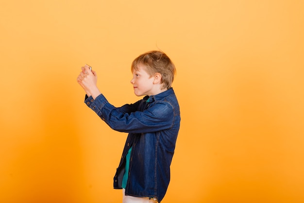 Der kleine Junge telefoniert auf gelbem Hintergrund