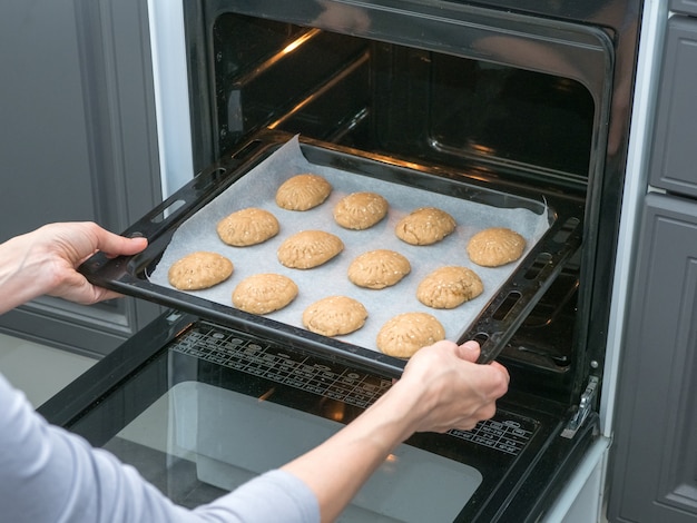 Der Koch backt Kekse im Ofen in der Küche. Shortbread-Kekse im Ofen backen. Manuelle Herstellung von Cookies für den Urlaub.