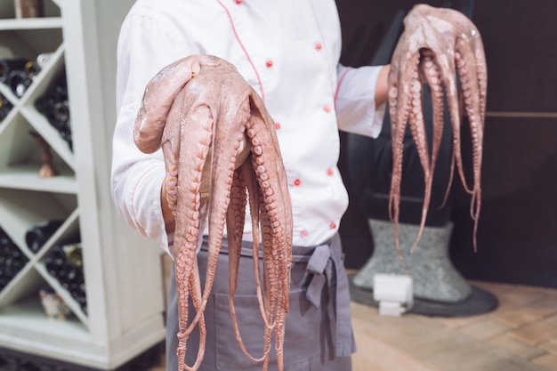 Der Koch hält eine Krake in der Hand.