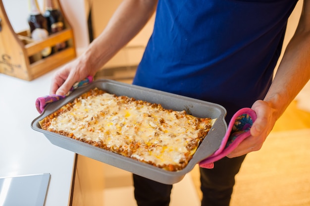 Der Koch nahm die fertige Lasagne aus dem Ofen. Wir bleiben zu Hause und kochen Lasagne.