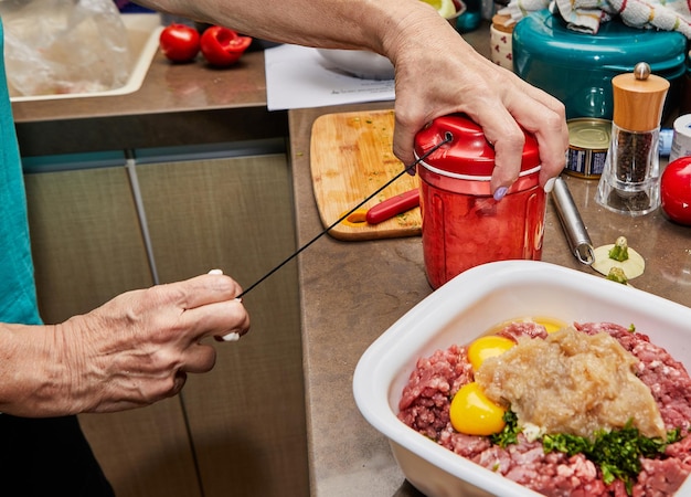 Foto der koch schlägt die eier mit einem handschläger, um sie zum hackfleisch hinzuzufügen