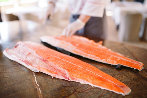 Der Koch schneidet den Lachs auf dem Tisch.