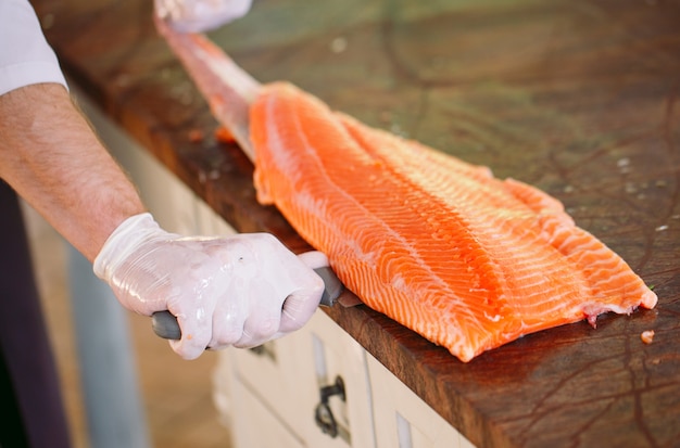 Der Koch schneidet den Lachs auf dem Tisch