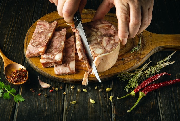 Foto der koch schneidet die muskeln mit einem messer auf dem küchenbrett in stücke, bevor er köstliche sandwiches zubereitet. schnelles snack-konzept mit kopfkäse und aromatischem rosmarin