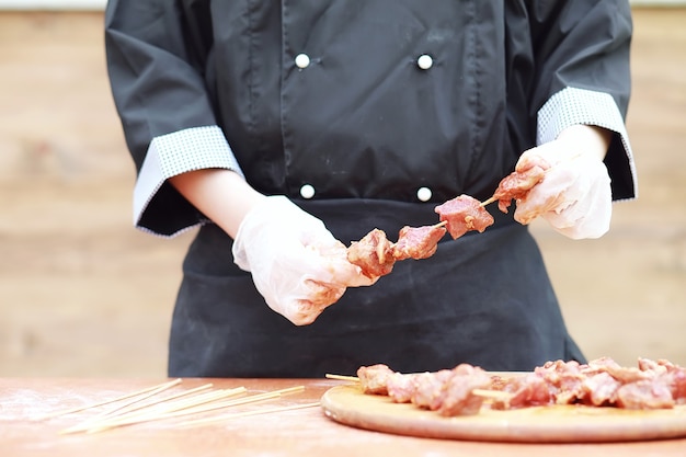 Der Koch schneidet Fleisch zum Grillen auf dem Tisch