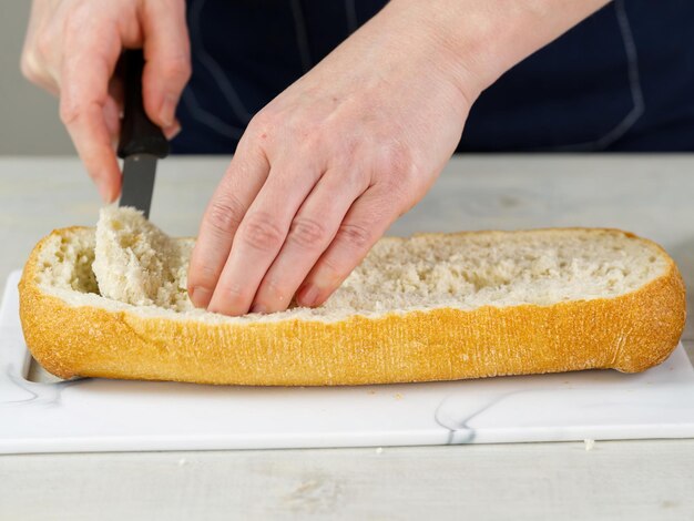 Der Koch schneidet frisches Ciabatta-Brot Zieht das Fruchtfleisch aus dem Inneren heraus Macht eine Basis zum Füllen von Brot Riesiger Sandwich-Herstellungsprozess aus nächster Nähe