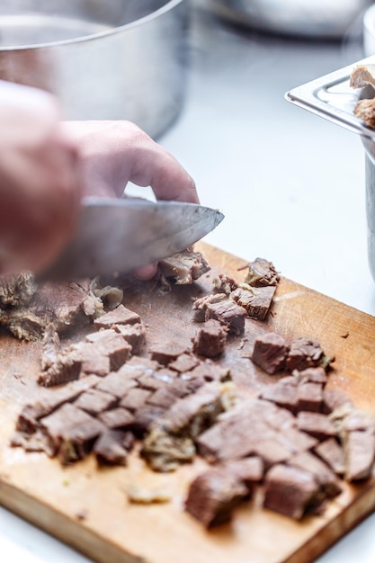 Der Koch schneidet gekochtes Rindfleisch