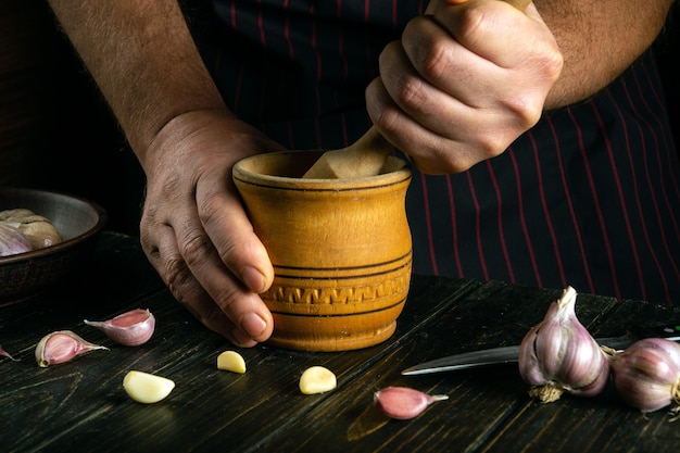 Der Koch zerkleinert Knoblauch auf dem Küchentisch, bevor er es dem Essen hinzufügt.