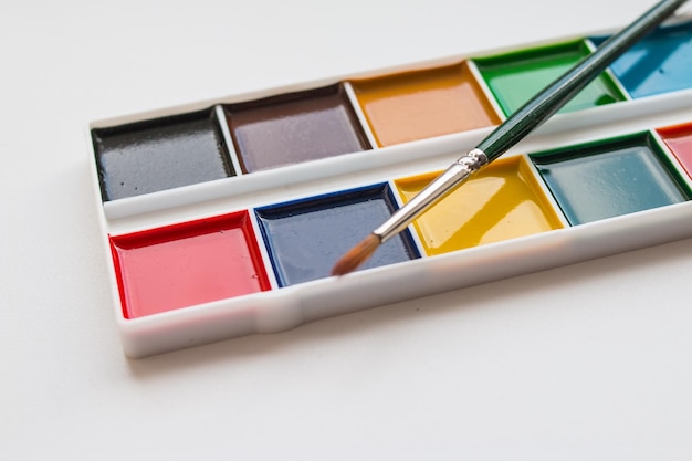 Foto der komplette satz aquarellfarben auf weißem hintergrund. aquarellfarben in einer plastikbox. verschiedene aquarellfarben in der palette. kopierraum