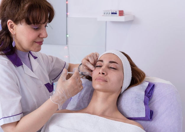 Der Kosmetiker führt verjüngende Anti-Falten-Füllstoff-Injektionen mit Hyaluronsäure-Füllstoff im Gesicht einer Frau durch. Ästhetische Kosmetologie für Frauen in einem Schönheitssalon
