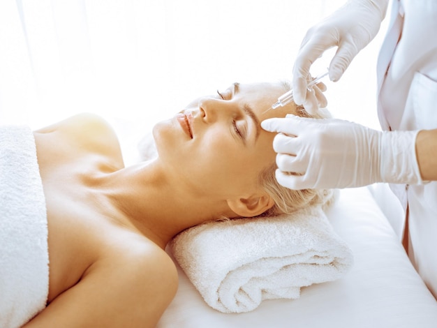 Der Kosmetikerarzt führt in der Klinik eine Schönheitsbehandlung am weiblichen blonden Gesicht mit einer Spritze durch. Kosmetische Medizin und Chirurgie, Konzept für Schönheitsinjektionen.