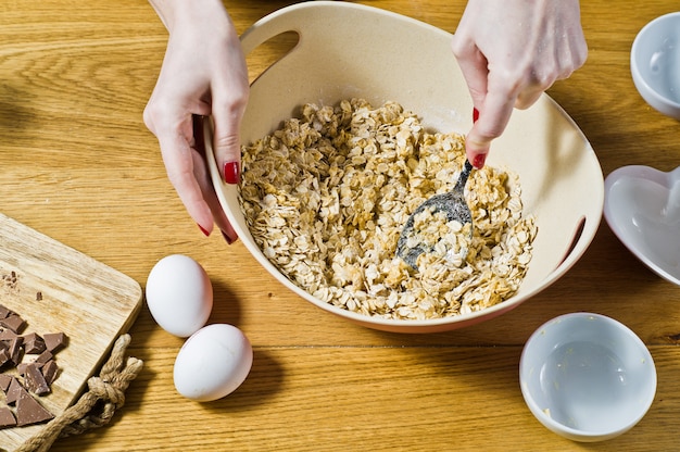 Der Küchenchef bereitet Haferkekse zu, mischt Zutaten: Haferflocken, Butter, Zucker, Eier, Schokolade.