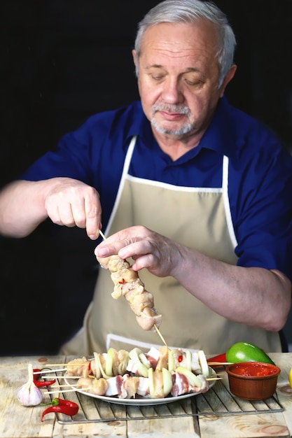 Der Küchenchef bereitet Hühnchen-Spieße auf Holzstäbchen zu