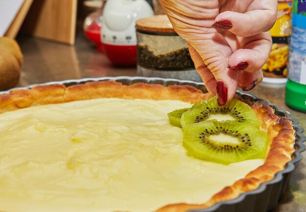 Der Küchenchef bereitet Kiwi-Kuchen zu, indem er die Kiwi im Kreis ausbreitet