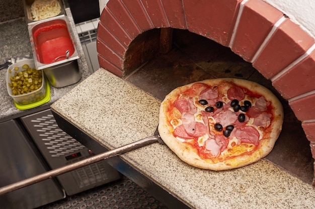 Der Küchenchef bereitet Pizza im traditionellen Steinofen zu.