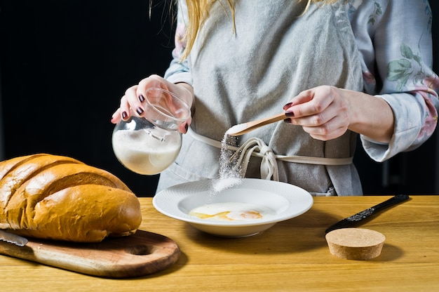 Der Küchenchef gießt Zucker in einen Teller. Das Konzept des Kochens von French Toast.