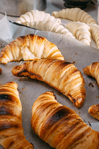 Der Küchenchef kocht morgens in der Küche Croissants auf dem Tisch fertige und rohe Croissants und die gleichen Zutaten für ihre Zubereitung