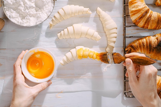 Der Küchenchef kocht morgens in der Küche Croissants auf dem Tisch fertige und rohe Croissants und die gleichen Zutaten für ihre Zubereitung