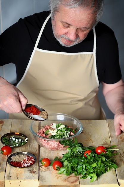 Der Küchenchef lädt Gewürze in eine Schüssel mit Hackfleisch