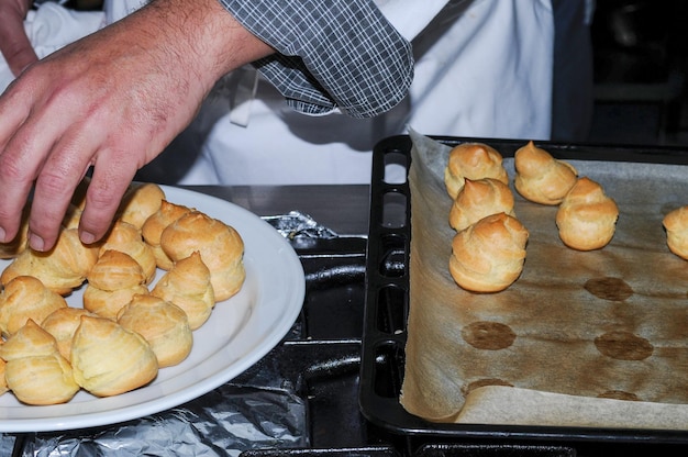 Der Küchenchef nimmt die Profiterole-Cupcakes vom Backblech