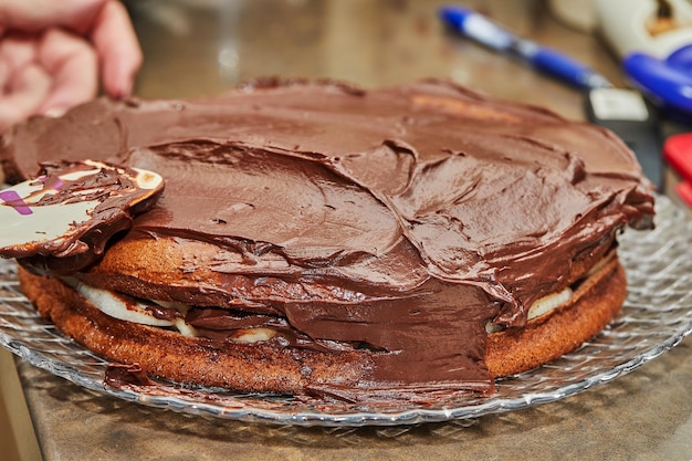Der Küchenchef überzieht den Kuchen mit Schokoladenganache, um Schokoladenkuchen mit Birnen und Walnüssen zuzubereiten