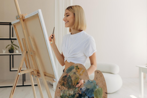 Der Künstler malt im Studio Attraktives Mädchen, das ein weißes T-Shirt trägt