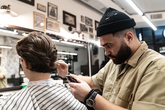 Der Kunde erhält einen Haarschnitt und ein Haarstyling in einem Schönheitssalon. Barber dient dem Kunden.