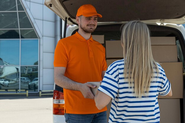 Der Kurier übergibt das Paket dem Kunden in der Nähe des Autos mit den Paketen